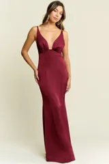 Vestido largo de satén color bordó, con escote profundo en V, tirantes finos y espalda descubierta. Presenta un corte ajustado en el torso que se ensancha suavemente hacia el ruedo.