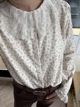 Camisa de algodón color crema con estampado de hojas marrones, cuello babero y puños de encaje.