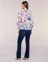 Blusa de gasa liviana blanca con estampado floral en tonos azules y rosados, escote en V, mangas 3/4 abullonadas con puños elásticos y corte fluido.