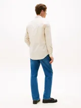 Camisa de manga larga color beige claro, corte slim fit, con cuello abotonado, cierre con botones y logo de Tommy Hilfiger bordado en el pecho.