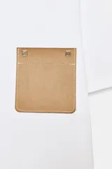 Camiseta blanca de algodón, corte regular, cuello redondo y manga corta, con bolsillo cuadrado de tejido efecto piel color camel en el pecho.