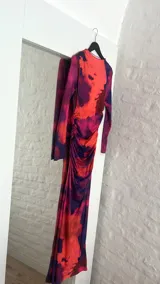 Vestido midi ajustado con estampado abstracto en tonos naranja, rosa y azul. Tiene cuello alto y mangas largas.