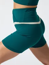 Short de entrenamiento color verde oscuro con cintura cruzada en forma de V y detalle en contratono beige.