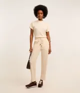 Pantalón zanahoria color crema, con cintura elástica, lazo, bolsillos laterales y superficie texturizada.