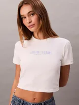 Remera cropped blanca de manga corta y cuello redondo, con logo gráfico de Calvin Klein impreso en el pecho.