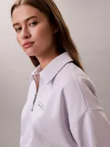 Buzo Calvin Klein de tejido french terry color lila claro, con cuello tipo polo y cierre de media cremallera. Cuenta con el logo de la marca bordado en el pecho y diseño de manga larga.