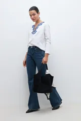 Remera blanca de manga larga con bordado floral azul en el escote.