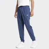 Pantalón deportivo New Balance modelo Sport Essentials Woven Jogger, color azul, confeccionado en poliéster reciclado. Presenta cintura elástica con cordón de ajuste, bolsillos laterales y puños ajustados en los tobillos.