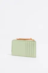 Monedero Bimba y Lola de piel vacuna con textura granulada, color verde menta. Presenta cierre con cremallera, tirador de cordón en color naranja, tarjetero exterior y logo de la marca grabado en dorado.