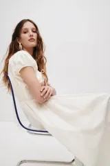 Vestido midi color blanco en tejido liviano, con escote redondo fruncido y abertura en V con tira fina ajustable en el frente. Tiene mangas cortas abullonadas, cintura elástica en punto smock y falda acamponada de corte midi.