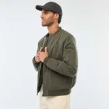 Campera estilo bomber color verde militar, con cierre frontal, cuello, puños y ruedo de tejido elástico acanalado. Presenta un bolsillo con cierre en la manga izquierda.