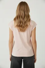 Remera blanca de algodón, de corte holgado, con cuello redondo a la base y mangas cortas con el dobladillo doblado hacia afuera.