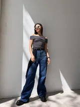 Top de bikini o crop top negro con estampado de lunares blancos, escote bardot (hombros descubiertos) y mangas cortas.