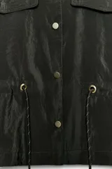 Cazadora satinada de color negro, con cuello subido, bolsillos con solapa en el pecho y cordón ajustable en la cintura. Cierre frontal con botones metálicos y mangas anchas.