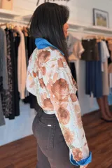 Camisa de broderie con estampado de rosas marrones sobre base blanca, manga larga, cuello camisero y detalles en denim azul.