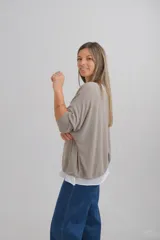 Sweater de punto color beige con diseño de doble capa, escote en V con detalle de vivo plateado y mangas largas. Presenta un corte amplio y holgado.