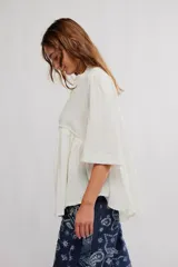 Blusa blanca con cuello mao y escote en V, de manga corta y corte amplio con fruncido frontal.