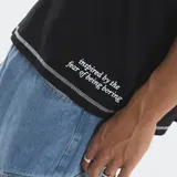 Remera negra de corte boxy con costuras a la vista en contraste de color blanco. Presenta un pequeño logo estampado en el centro del pecho y una frase bordada en el bajo lateral. Posee mangas cortas y cuello redondo.