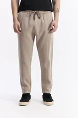 Pantalón de jogging negro de algodón y poliéster, con puños ajustados en los tobillos, cintura elástica con cordón y costuras verticales marcadas en el frente.