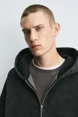 Sudadera con capucha y cierre de cremallera, de corte relajado (relaxed fit), confeccionada en algodón con interior afelpado. Presenta bolsillos frontales tipo canguro y acabados en rib. El tejido tiene un efecto lavado que le da un color negro desgastado.