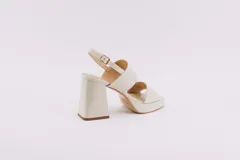 Sandalias de plataforma color crema, con tiras anchas de charol y hebilla ajustable en el tobillo.