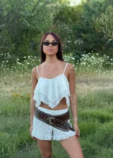 Top corto de tirantes finos en color blanco, con diseño de capas con terminación en punta y textura delicada en relieve.