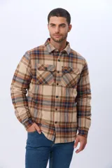 Campera estilo leñadora de viyela a cuadros en tonos beige, marrón y azul, con interior forrado en corderito, cierre frontal con botones y dos bolsillos con solapa en el pecho.