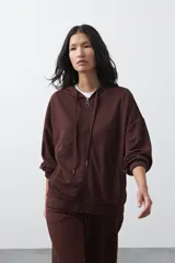 Campera con capucha y cierre frontal, de silueta relajada, hombros caídos y bolsillos laterales. Presenta terminaciones elastizadas en puños y ruedo, con líneas de recorte frontales y cierre metálico con tirador circular.