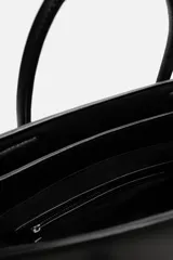 Bolso bandolera negro con detalle de cinturón, compartimento principal con cierre de imán, bolsillo interno con cremallera, doble asa de mano y asa de hombro ajustable y extraíble.