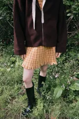Chaqueta de punto color marrón con capucha desmontable en tejido técnico a tono. Presenta cierre frontal con cremallera, bolsillos delanteros y mangas largas con doble puño elástico.