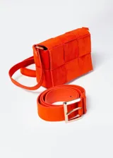 Mini bag color naranja con diseño acolchado tipo tejido, correa de hombro y cinto a juego.