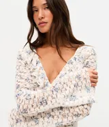 Blusa Blue Steel de encaje con estampado floral, escote en V y volados frontales, de manga larga.