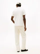 Chomba de corte regular de Tommy Hilfiger, color blanco, con cuello polo y cierre de cremallera de 1/4. Cuenta con mangas cortas y detalle del logo bordado en el pecho.