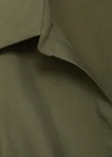 Vestido midi de diseño cruzado en color verde oliva, con cuello camisero, cierre frontal de botones y lazo lateral para ajustar en la cintura. Presenta mangas largas con puños abotonados y una abertura lateral pronunciada en el bajo.