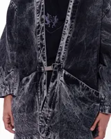 Kimono negro con efecto lavado, confeccionado en algodón. Tiene corte amplio, mangas 3/4, bolsillos laterales y cierre frontal con hebilla metálica.