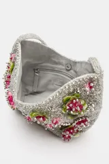 Bolso de hombro plateado cubierto de abalorios y cuentas, decorado con apliques florales tridimensionales en tonos verde y fucsia. Cuenta con un asa corta para el hombro, cierre de clip imantado y bolsillo interior con cremallera.