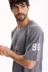 Remera gris de manga corta con lavado acid wash y diseño raglán con vivos en contraste. Presenta estampa frontal con el texto "WEST DIVISION" y número en la manga.