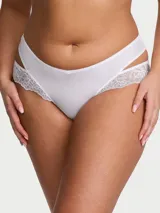 Panty tipo cheeky color blanco, confeccionado en suave microfibra con tiro bajo y detalles de encaje elástico en los laterales con aberturas que generan un efecto de capas.
