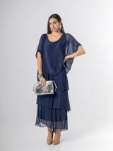Vestido largo azul marino de seda italiana, con diseño de volados escalonados en la falda y una sobrecapa superior con mangas cortas amplias.