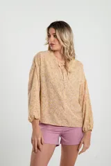 Blusa amarilla con estampado floral, cuello redondo con lazo y mangas largas abullonadas.