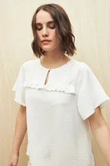 Blusa negra con textura, canesú con encaje, volados, corte fluido y mangas cortas amplias.