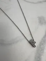 Collar de acero quirúrgico plateado con dije de letra F incrustado de strass.