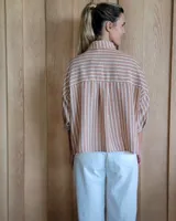 Camisa celeste a rayas verticales blancas, de corte holgado, manga 3/4 y cuello camisero.