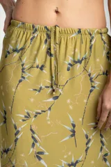 Falda midi color verde oliva con estampado de ramas en negro y blanco. Tiene corte evasé, cintura alta con cordón ajustable y abertura lateral.