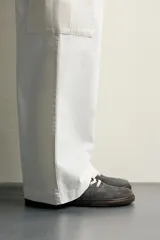 Zapatilla deportiva barefoot fabricada en piel con acabado serraje de color marrón, con cordones en contraste y suela fina de goma.