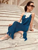 Vestido azul metálico con cuello plateado, sin mangas, corte recto, largo midi con flecos y tajos laterales.