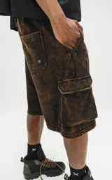 Bermuda cargo de algodón rústico, color marrón oscuro con efecto desgastado (acid wash/oxidado). Presenta un calce oversize, cintura elástica y grandes bolsillos laterales con tapa.
