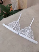 Conjunto de lencería compuesto por un bralette triangular de encaje floral con breteles regulables y una bombacha tipo tanga de encaje a juego con laterales ajustables.
