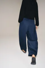 Pantalón de tiro medio con pierna ancha, confeccionado en mezcla de lyocell y viscosa. Cuenta con cintura elástica ajustable con cordones y bolsillos laterales ocultos en la costura.