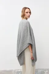 Ruana de tejido de punto grueso en color gris, con diseño de cuello alto y terminaciones acanaladas en los bordes.